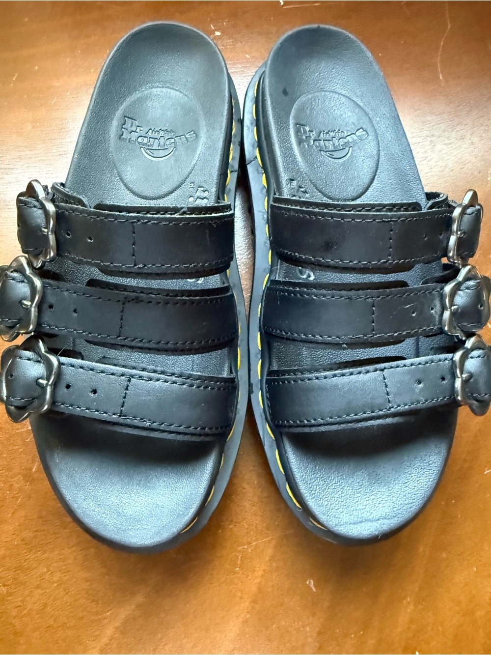 Dr. Martens Black Flower Triple-Buckle Slide Sandals with Yellow Stitching.